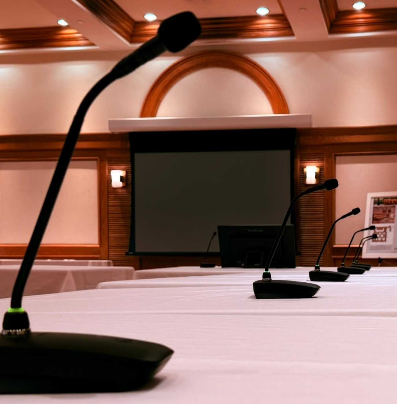 Executive boardroom with wireless tabletop microphones, large projection screen, and integrated audiovisual technology.