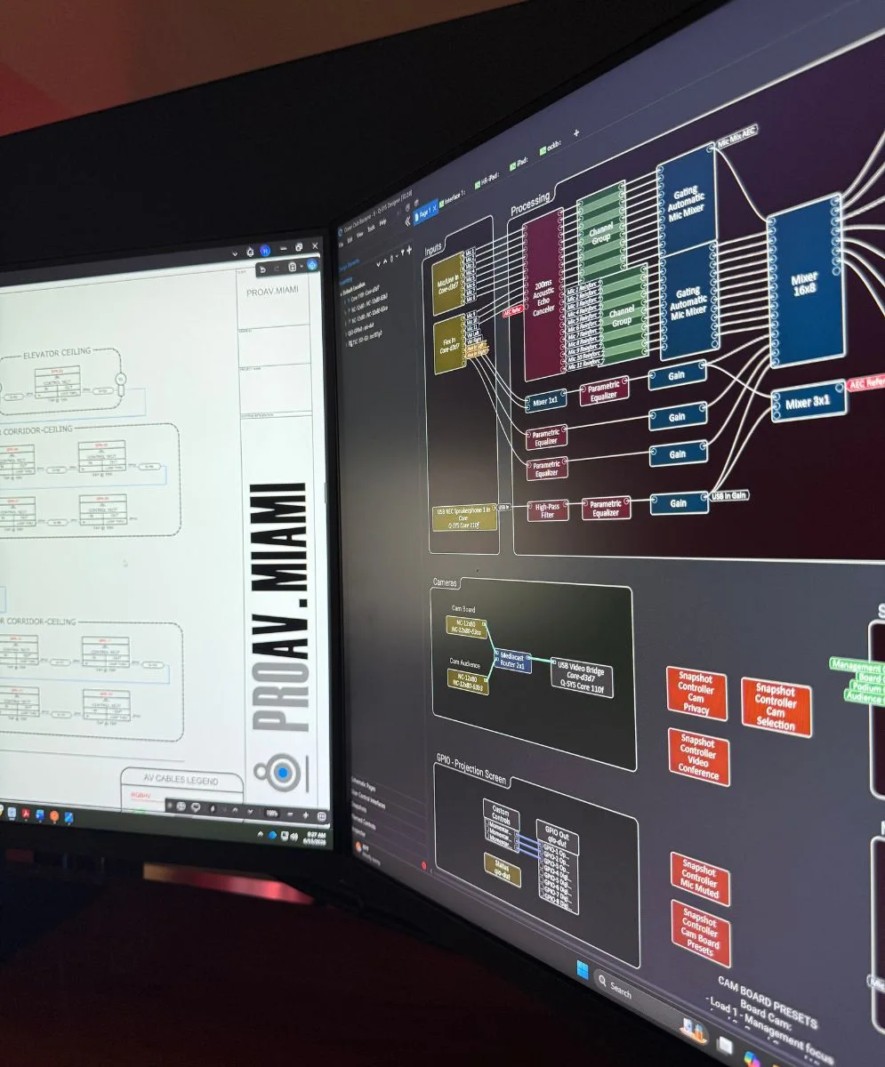 Commercial audiovisual workspace with control system programming, technical documentation, and integrated AV equipment.
