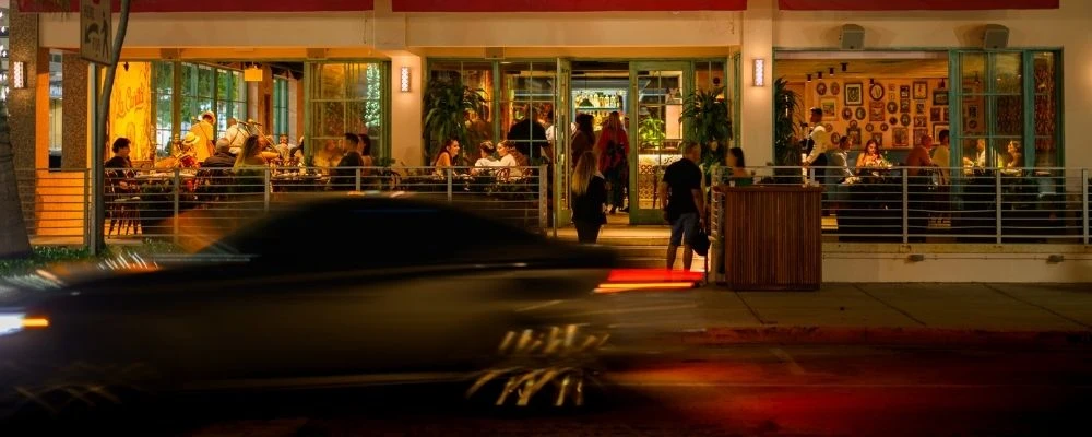 Restaurant entrance on Ocean Drive with inviting lighting and active evening dining atmosphere.