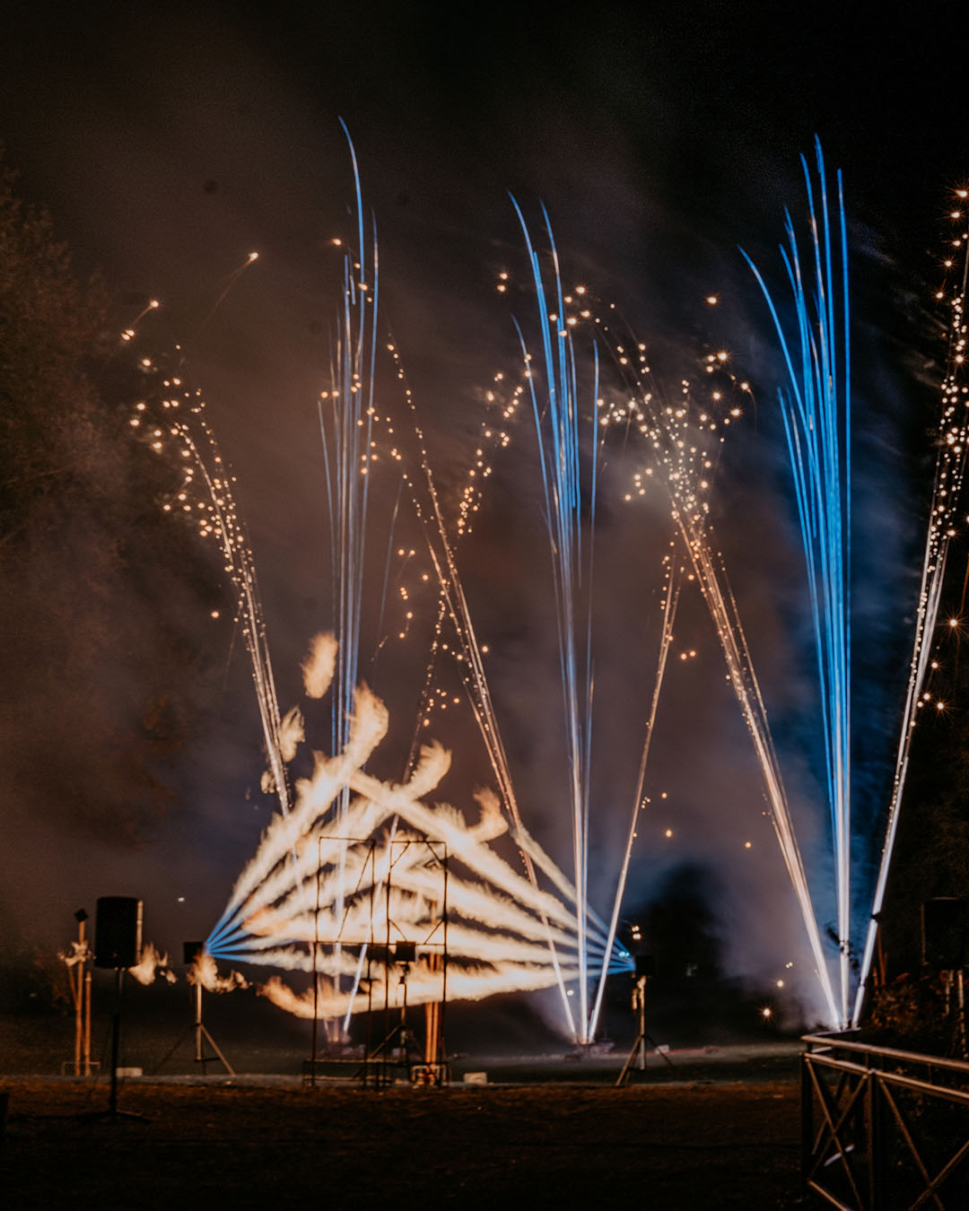 Feux d'artifice nocturnes avec étincelles bleues et dorées jaillissant dans la fumée, spectacle pyrotechnique !