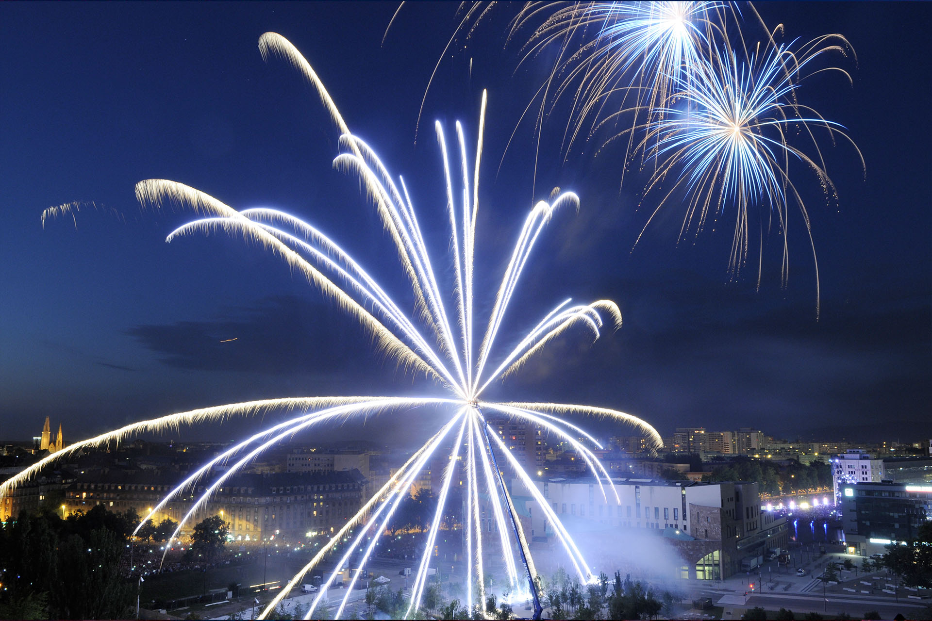 Feux d'artifice bleus et blancs explosant au-dessus de Strasbourg lors de la Fête Nationale