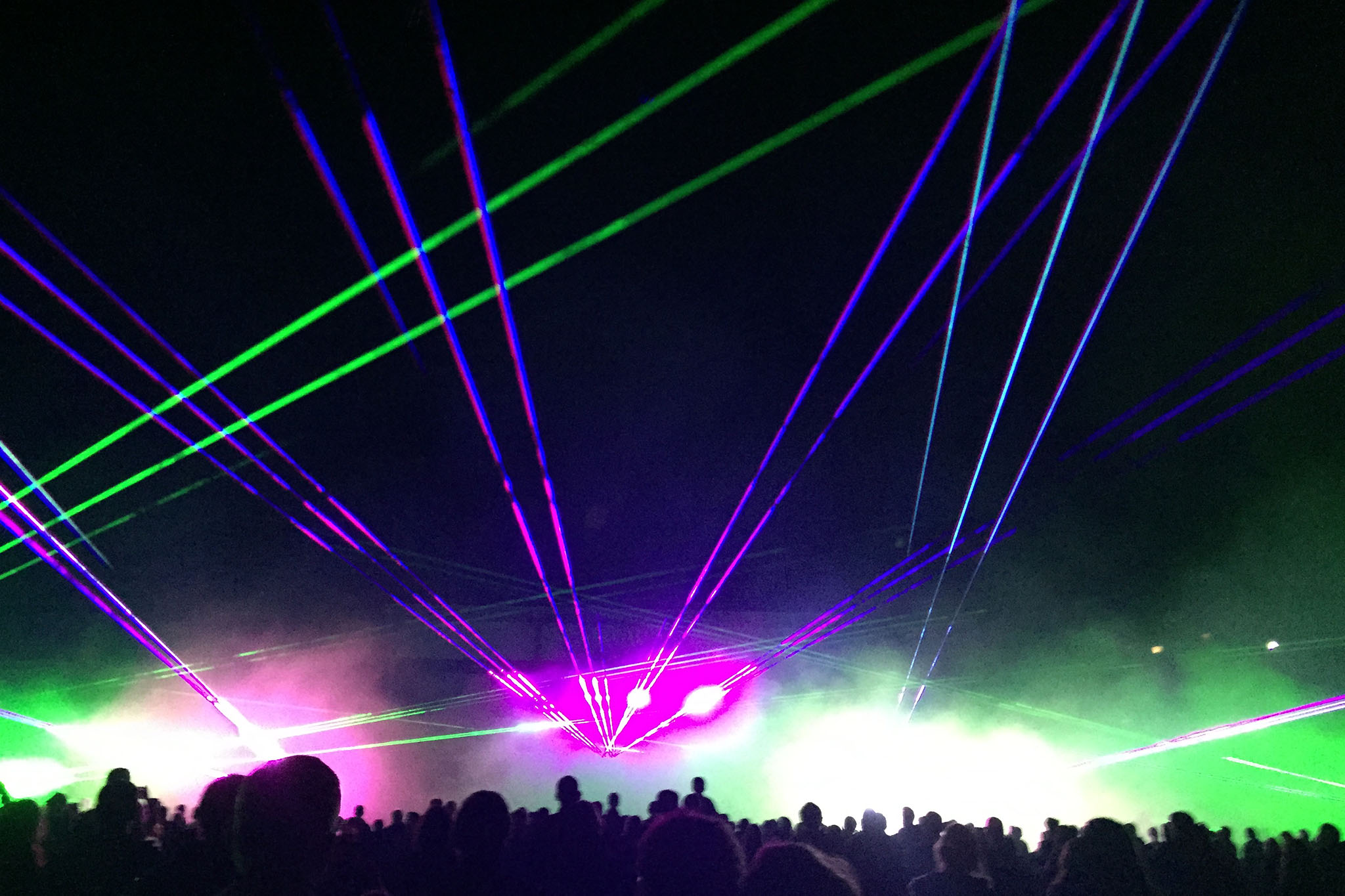 Faisceaux laser verts violets et bleus traversant le brouillard lors d'un spectacle nocturne Wagnon Events