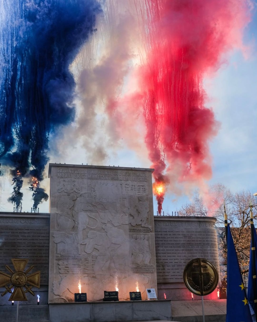 Effets pyrotechniques bleu, blanc, rouge s'élevant au-dessus d'un monument aux morts lors d'une cérémonie du 11 novembre dans les Hauts-de-France, spectacle de jour pour collectivité réalisé par Wagnon Events.