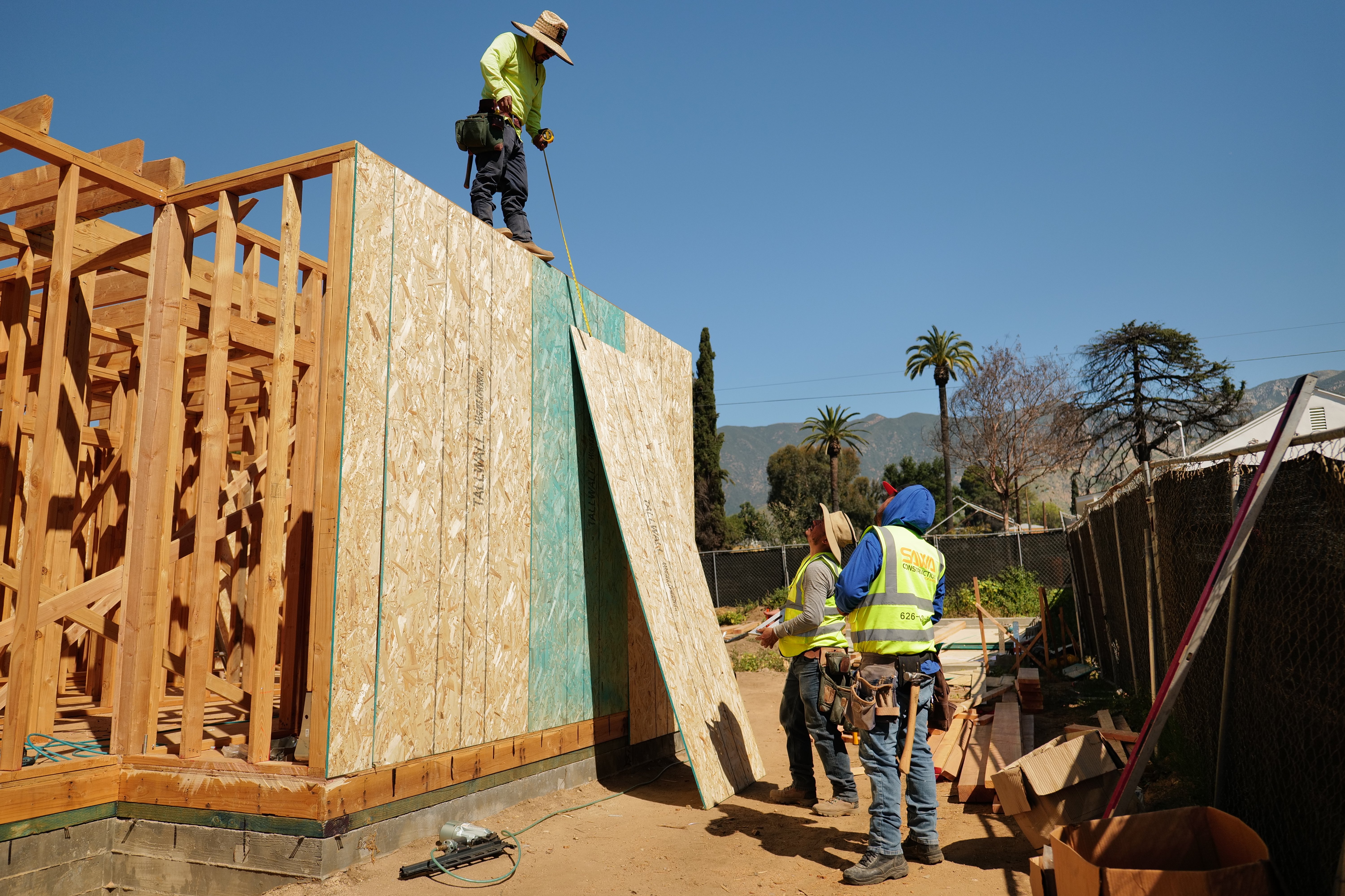 1st Choice crew building on a cleared, bare-soil Altadena rebuild lot with the San Gabriel Mountains behind