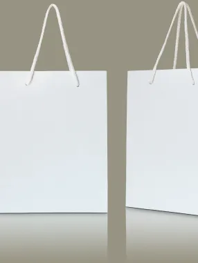 Duas sacolas de papel branco com alças de corda penduradas, sobre uma superfície refletora.