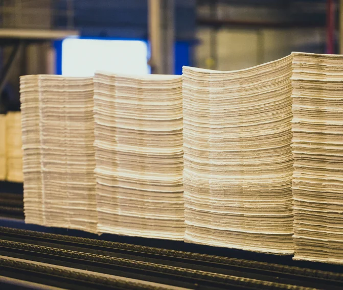Pilhas organizadas de folhas de celulose em linha de produção industrial.