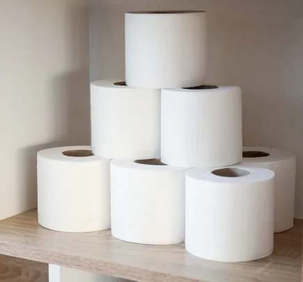 Sete rolos de papel higiênico branco empilhados em uma prateleira de madeira.