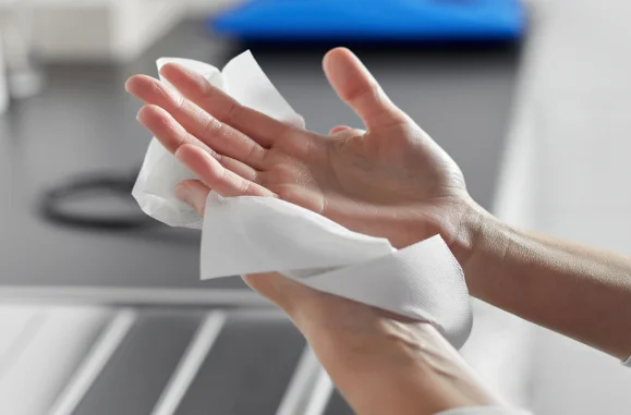 Pessoa limpando as mãos com lenço de papel branco.