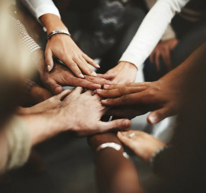 Mãos de pessoas diversas unidas em gesto de união e colaboração.