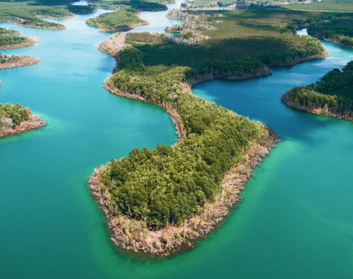 Vista aérea de ilhas verdes cercadas por água azul-turquesa em um ambiente natural.