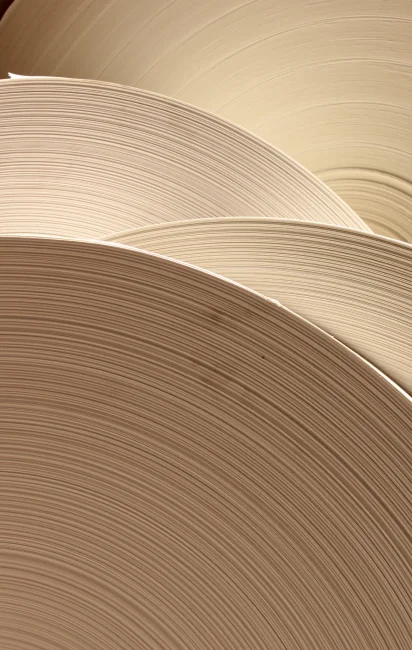Close-up of large rolls of uncoated paper with visible texture and layers.