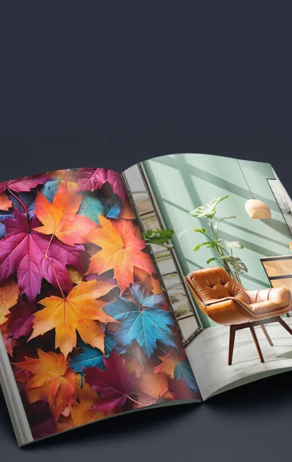 Revista aberta mostrando na página da esquerda folhas coloridas de outono em tons vibrantes de laranja, vermelho, roxo e azul, e na página da direita uma sala moderna com cadeira de couro marrom, planta e luz natural.