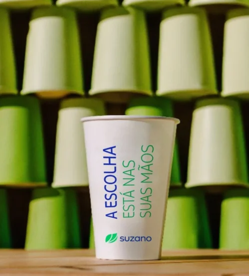 Copos descartáveis brancos e verdes empilhados, com um copo branco em destaque escrito 'A escolha está nas suas mãos' e logo da �ڰ�������.