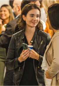 Mulher sorridente segurando uma xícara em uma reunião social informal.