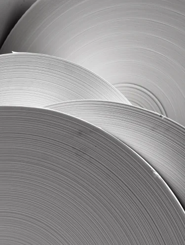 Rolos grandes de papel empilhados mostrando a textura circular das camadas.