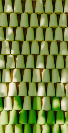 Vários copos descartáveis de plástico em tons de verde organizados em pilhas alinhadas.