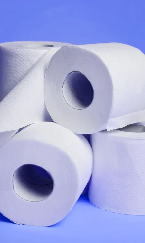 Papel higiênico branco empilhado sobre fundo azul.