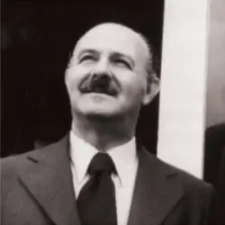 Retrato em preto e branco de um homem de meia-idade com bigode, vestindo terno, gravata e camisa social, olhando para cima com expressão serena.