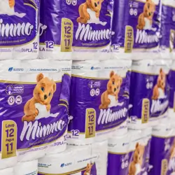 Pacotes de fraldas descartáveis Mimmo empilhados, com destaque para a embalagem roxa com imagem de bebê sorridente e texto promocional leve 12 pague 11.