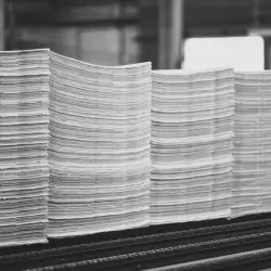 Pilha de folhas empilhadas uniformemente em linhas paralelas, sugerindo produção industrial de papel.