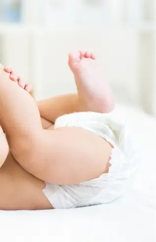 Close-up de um bebê deitado de bruços vestindo uma fralda branca.