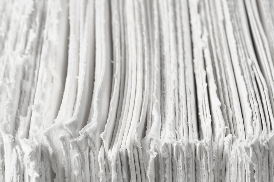 Pilha de folhas de papel branco reciclado com bordas irregulares e textura fibrosa.