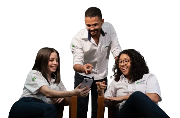 Três pessoas vestindo camisas brancas com logotipo verde estão sentadas e sorrindo enquanto olham para um celular.