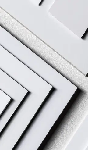 Vários pedaços de papel e papel cartão em tons de branco e cinza empilhados em camadas diagonais.