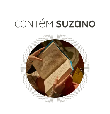 Pessoa lendo livro aberto com os dedos segurando as páginas, em um ambiente interno aconchegante.