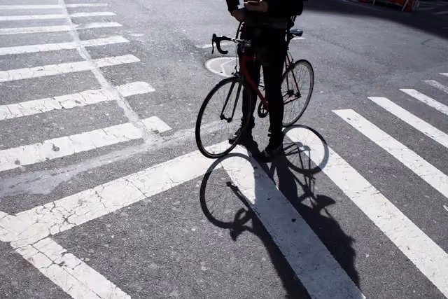 Ciclista parado na faixa de pedestres de uma cidade
