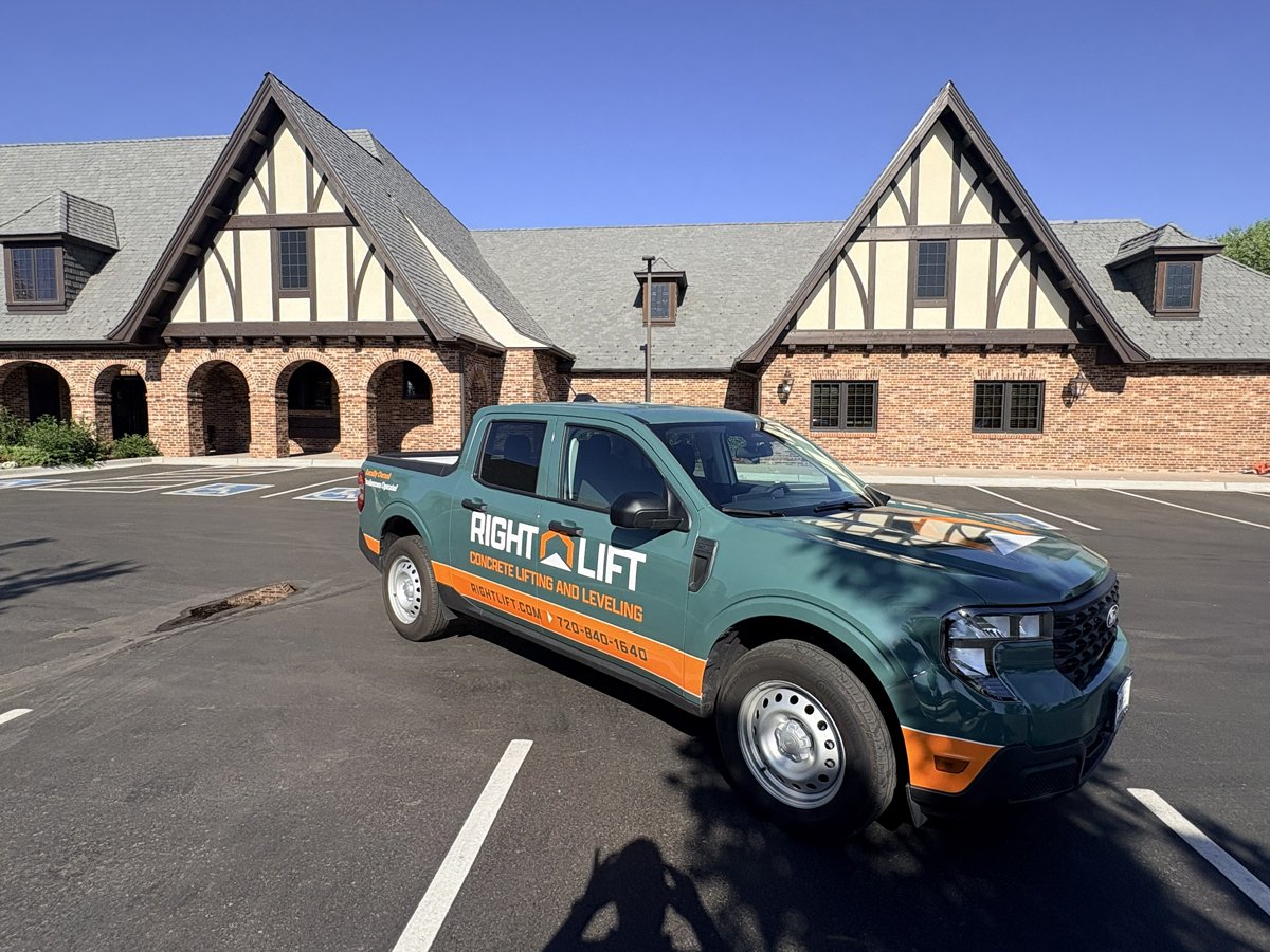 Rightlift green pickup truck with RightLift concrete lifting and leveling branding parked in front of a Tudor-style brick building.
