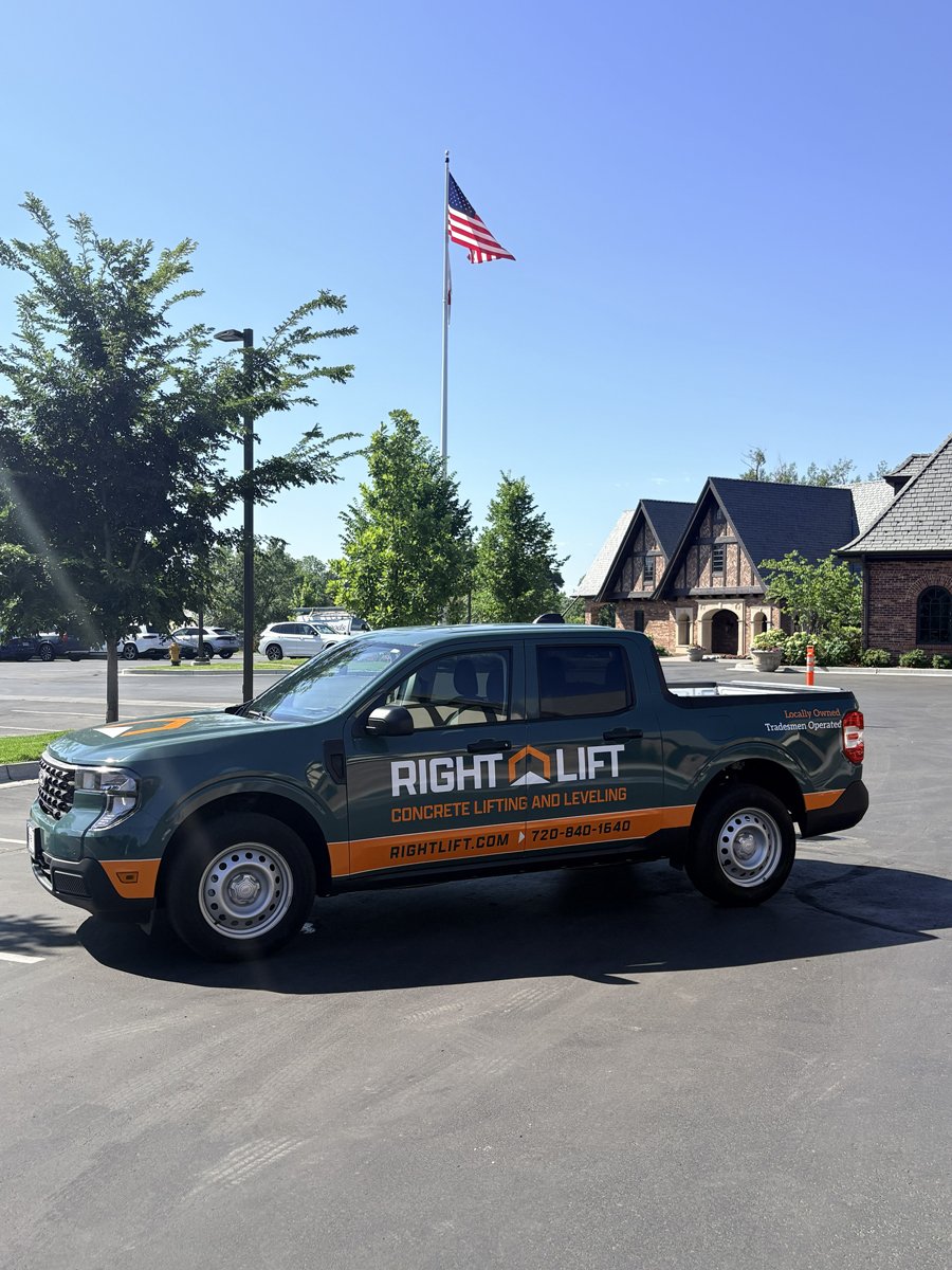 Pickup truck with RightLift concrete lifting company branding parked outside near trees and brick buildings.