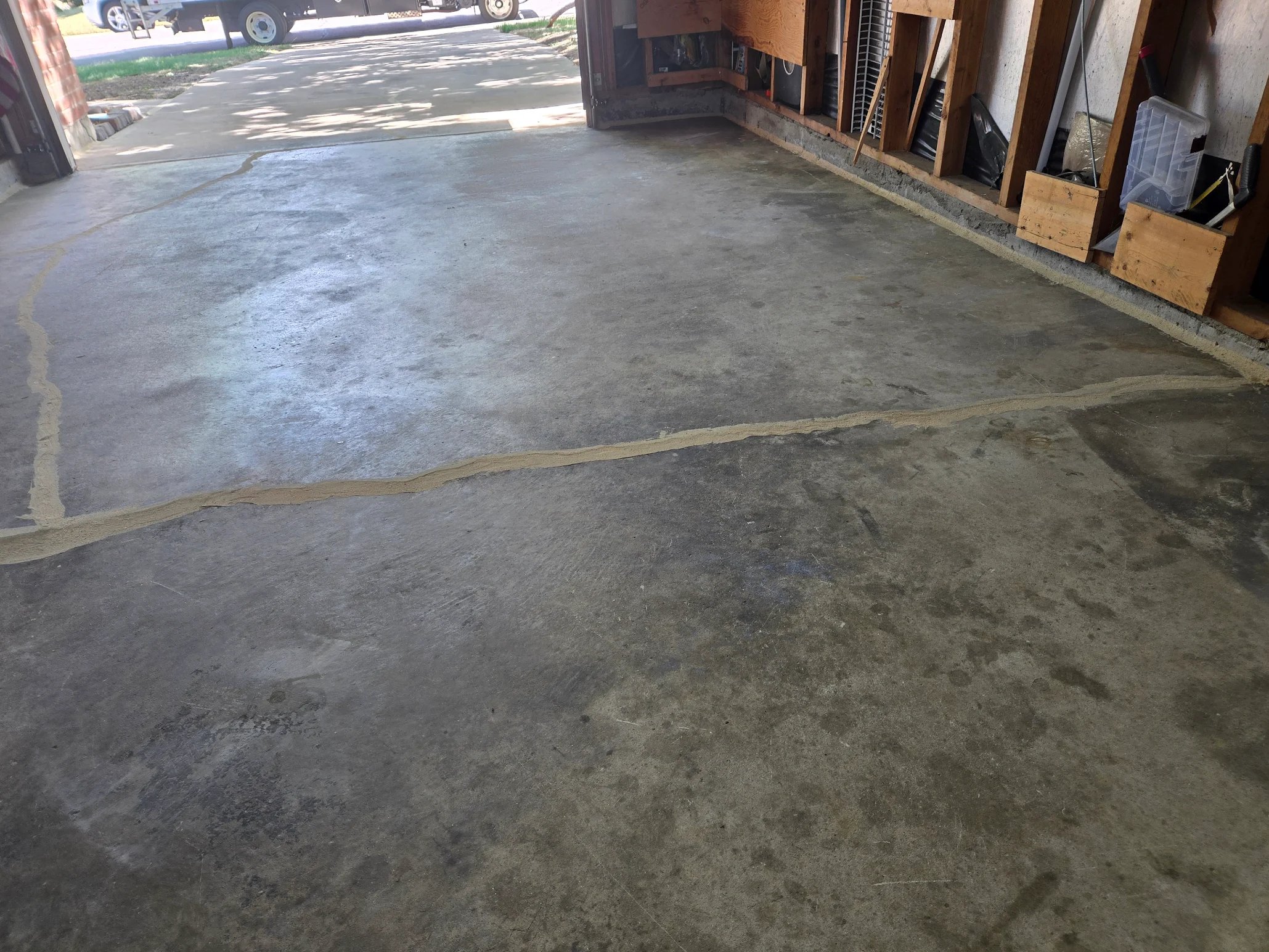 Concrete garage floor with visible cracks repaired using a filler material.