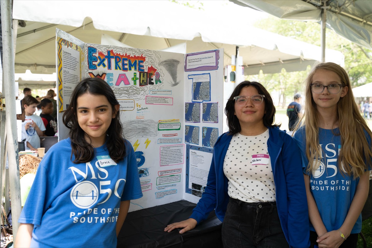 Three students stand beside their Extreme Weather project display at the Annual Student Symposium