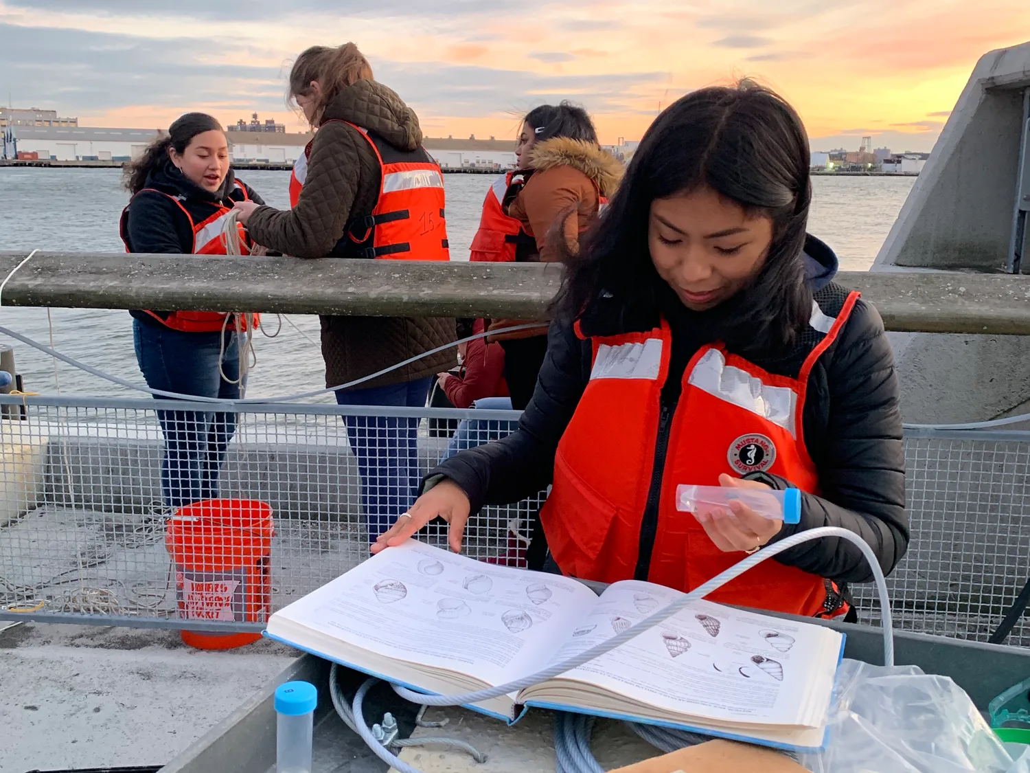 Student records observations from a boat at sunset