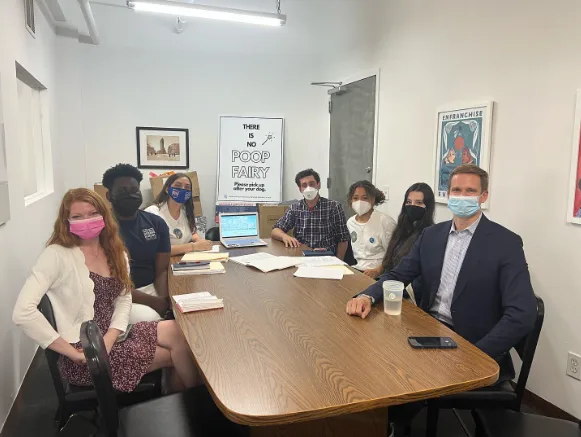 Students and adults meet around a conference table
