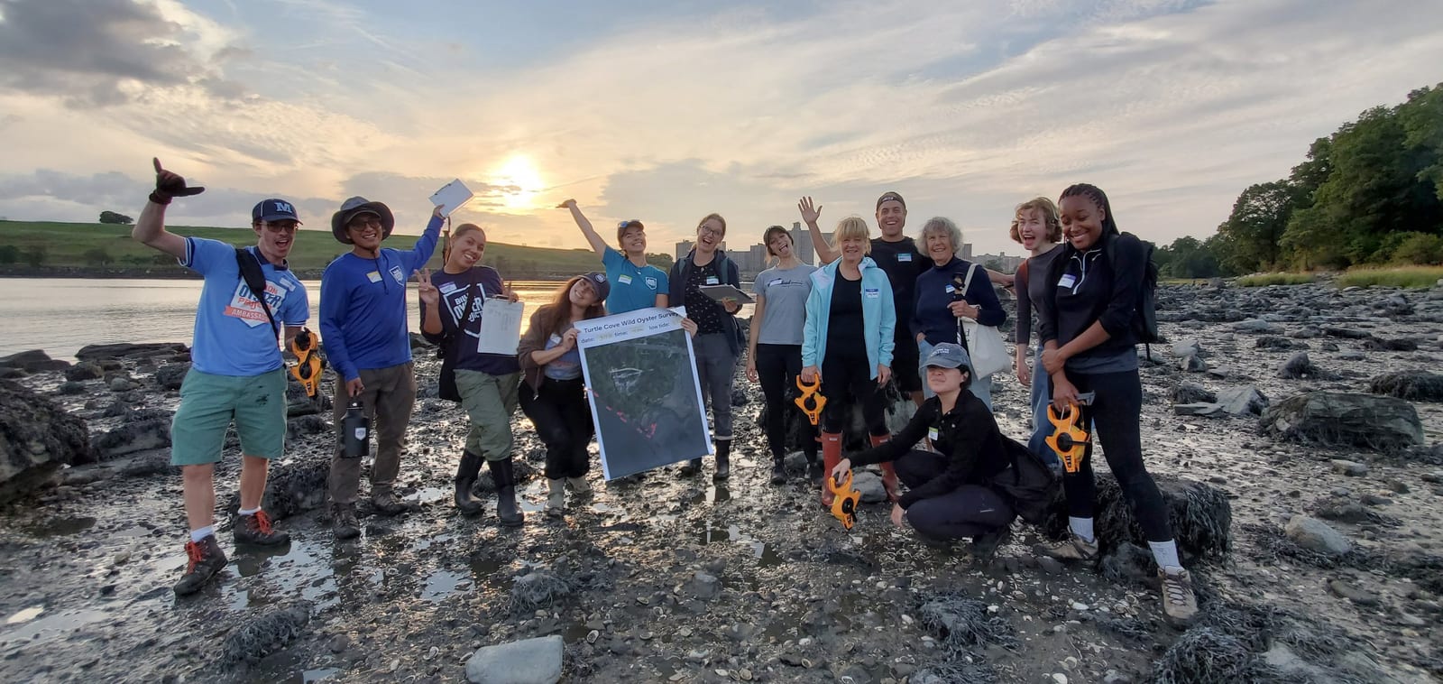 Students and educators explore a rocky shoreline at sunset
