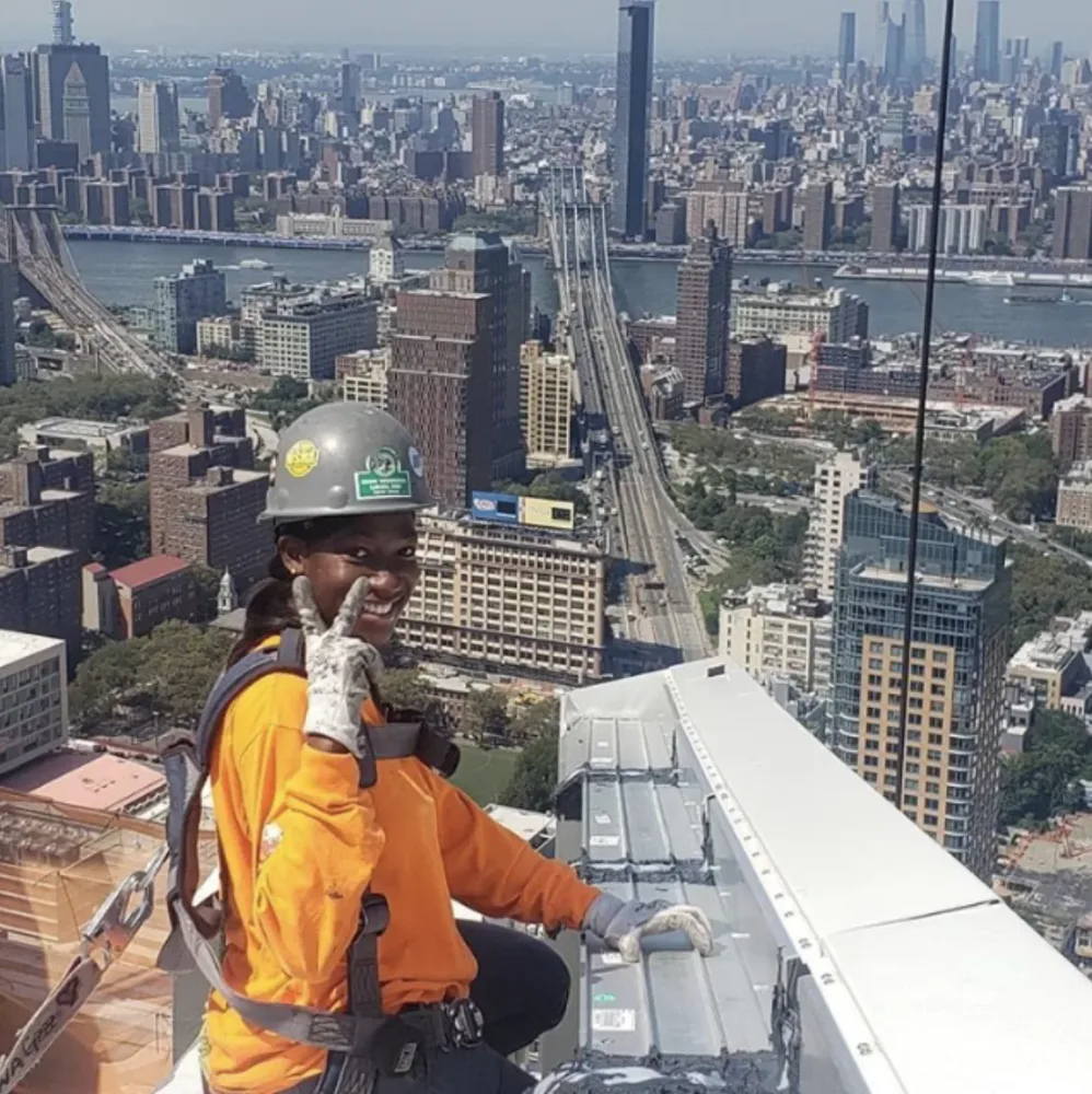 Awa Sylla poses above the city in construction safety gear
