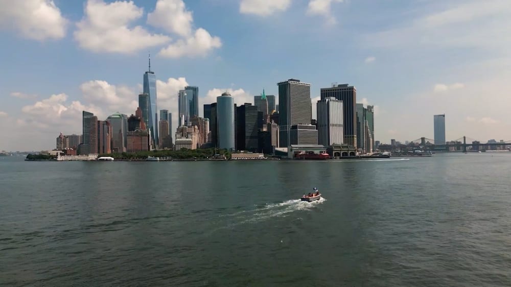 Boat travels across New York Harbor in front of the Lower Manhattan skyline