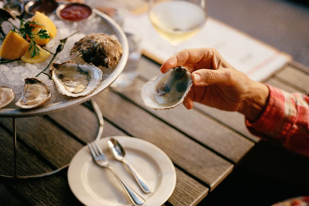 A diner seasons an oyster on the half shell