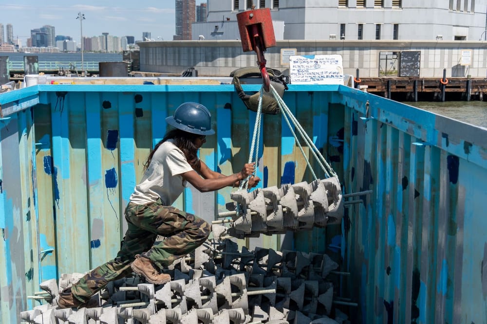 Worker handles reef structures inside a large blue container