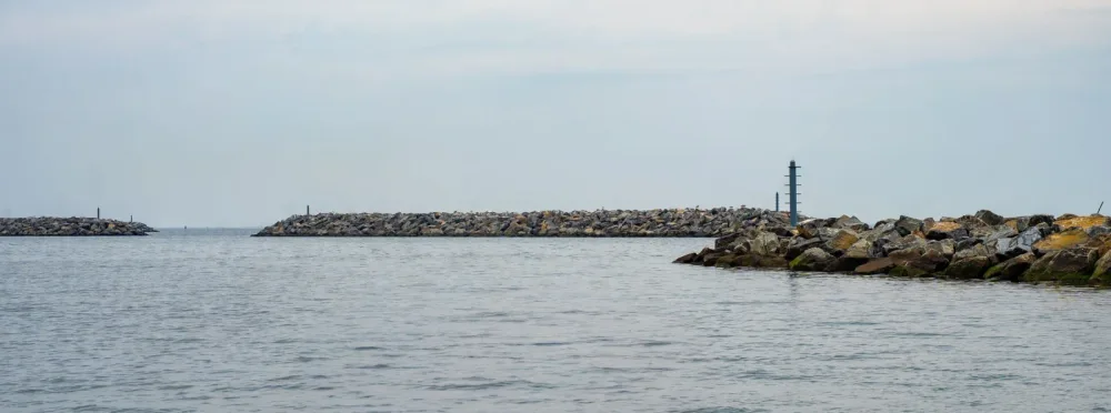 Rocky shoreline and breakwater beneath an overcast sky