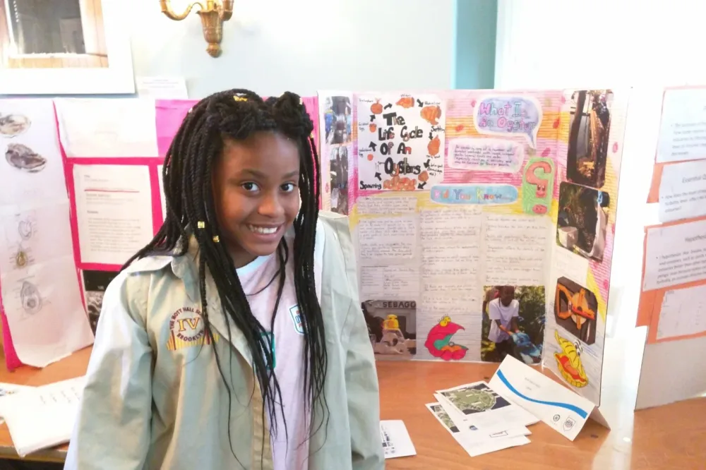 Student presents a science project beside a classroom display board