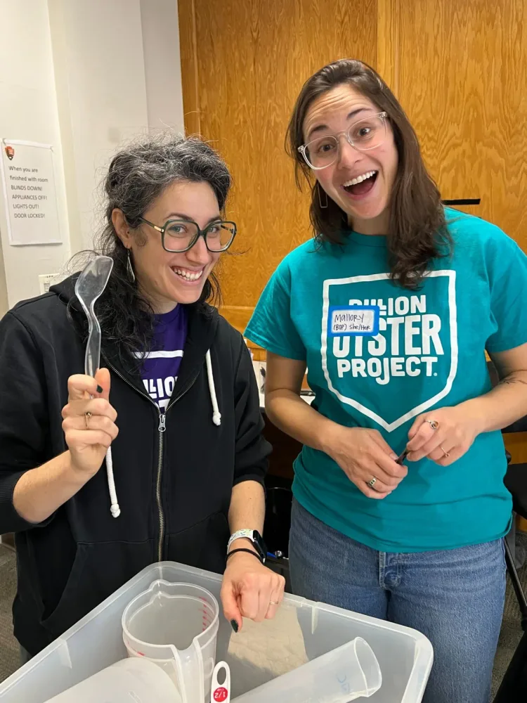 Two educators smile beside a water-testing activity