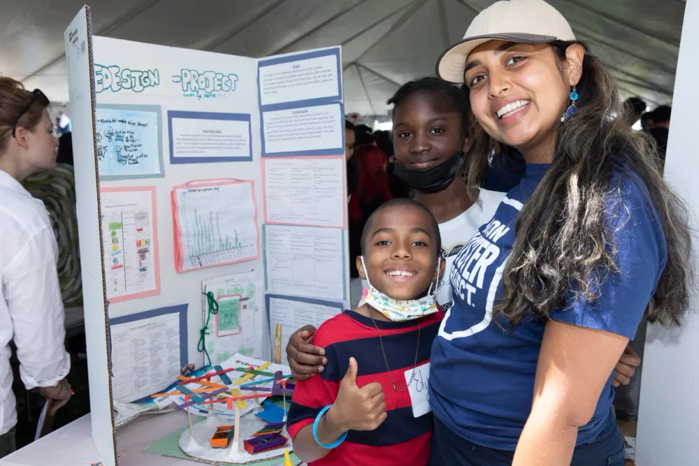 Student and educator stand beside a science-fair display
