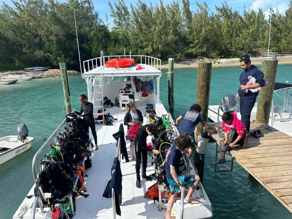 Divers prepare gear on a dock beside a boat