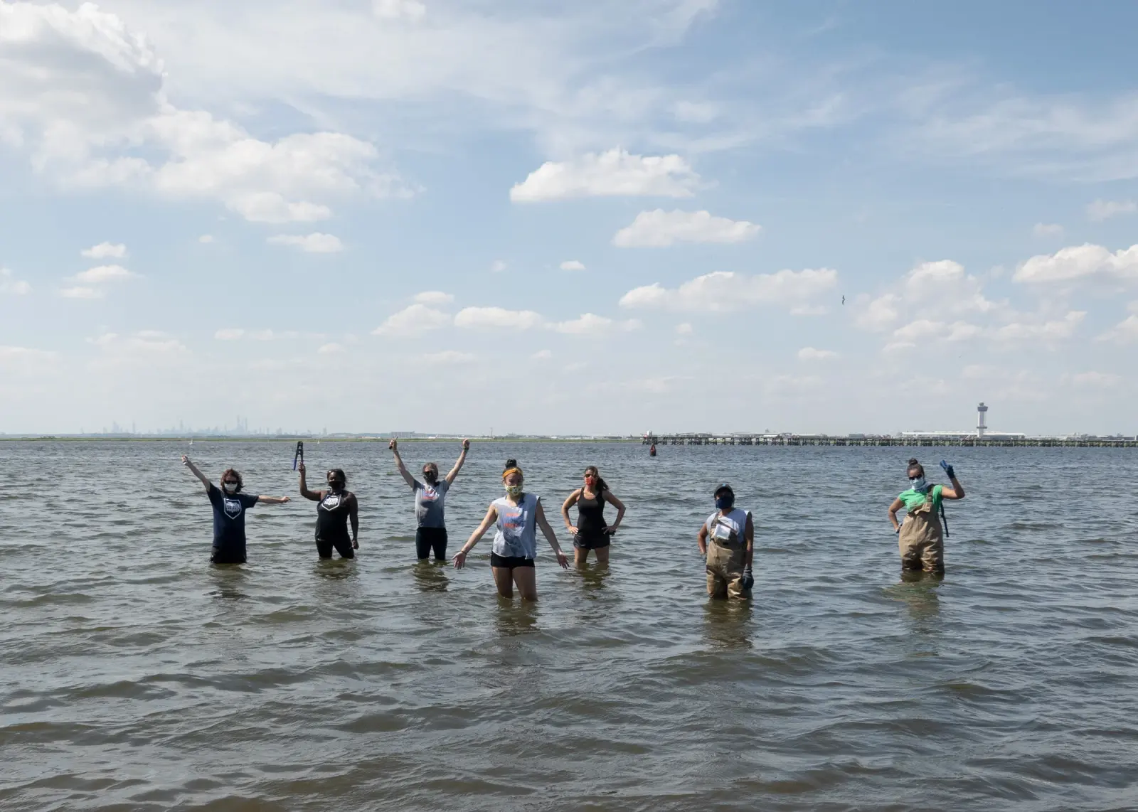 Volunteers celebrate while standing in shallow water at Bayswater Point