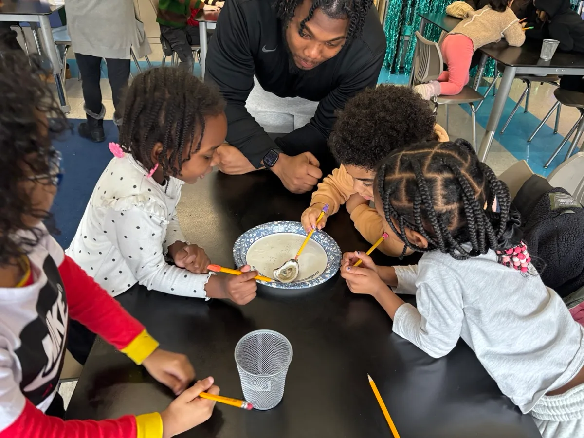 Children examine oysters together around a classroom table