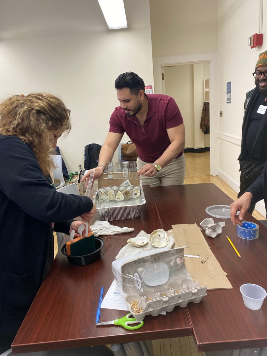 Educators examine oyster shells and classroom materials around a table