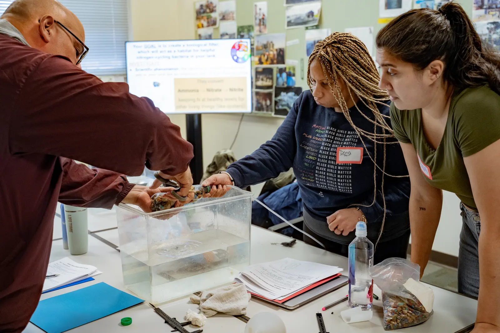 Three teachers work together to set up a biological filter for a classroom oyster tank.